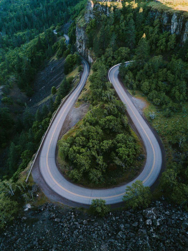 An aerial view of a winding horseshoe-shaped road surrounded by tall trees and green landscape in Mosier, Oregon. | DBT training and organizational consultation services in Portland and across Oregon