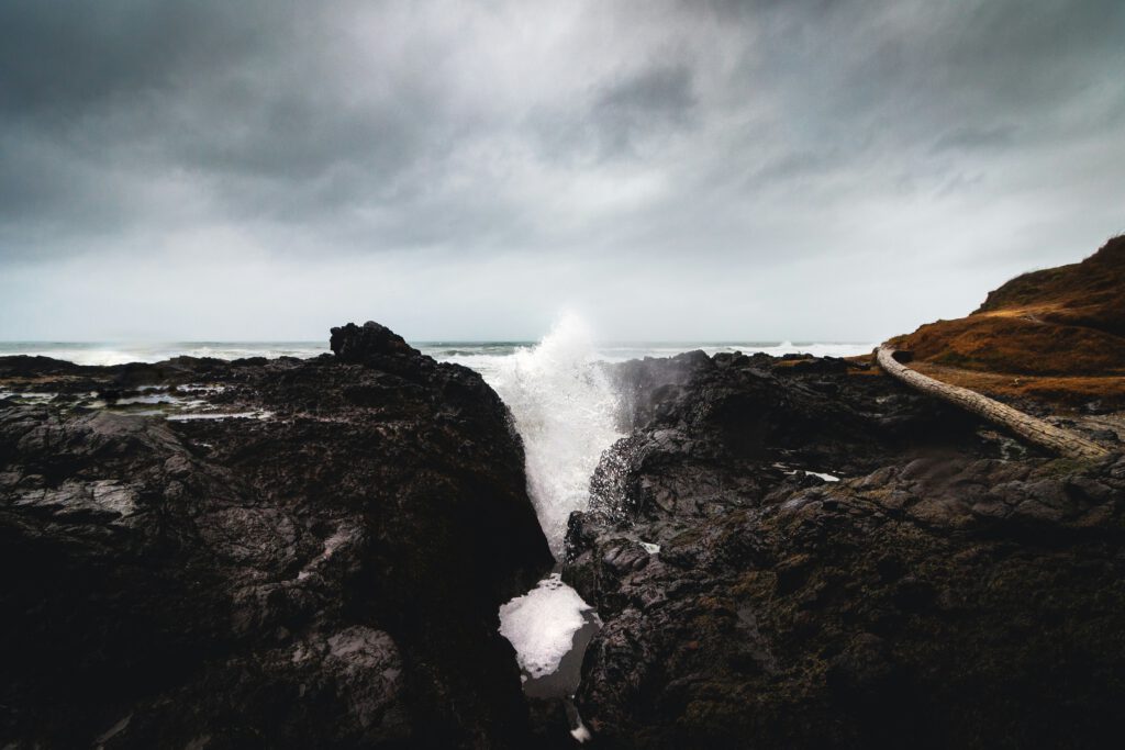 Ocean waves splashing and crashing against rocks on the Oregon coast. | Burnout therapy in Portland showing resilience and strength in facing life's challenges